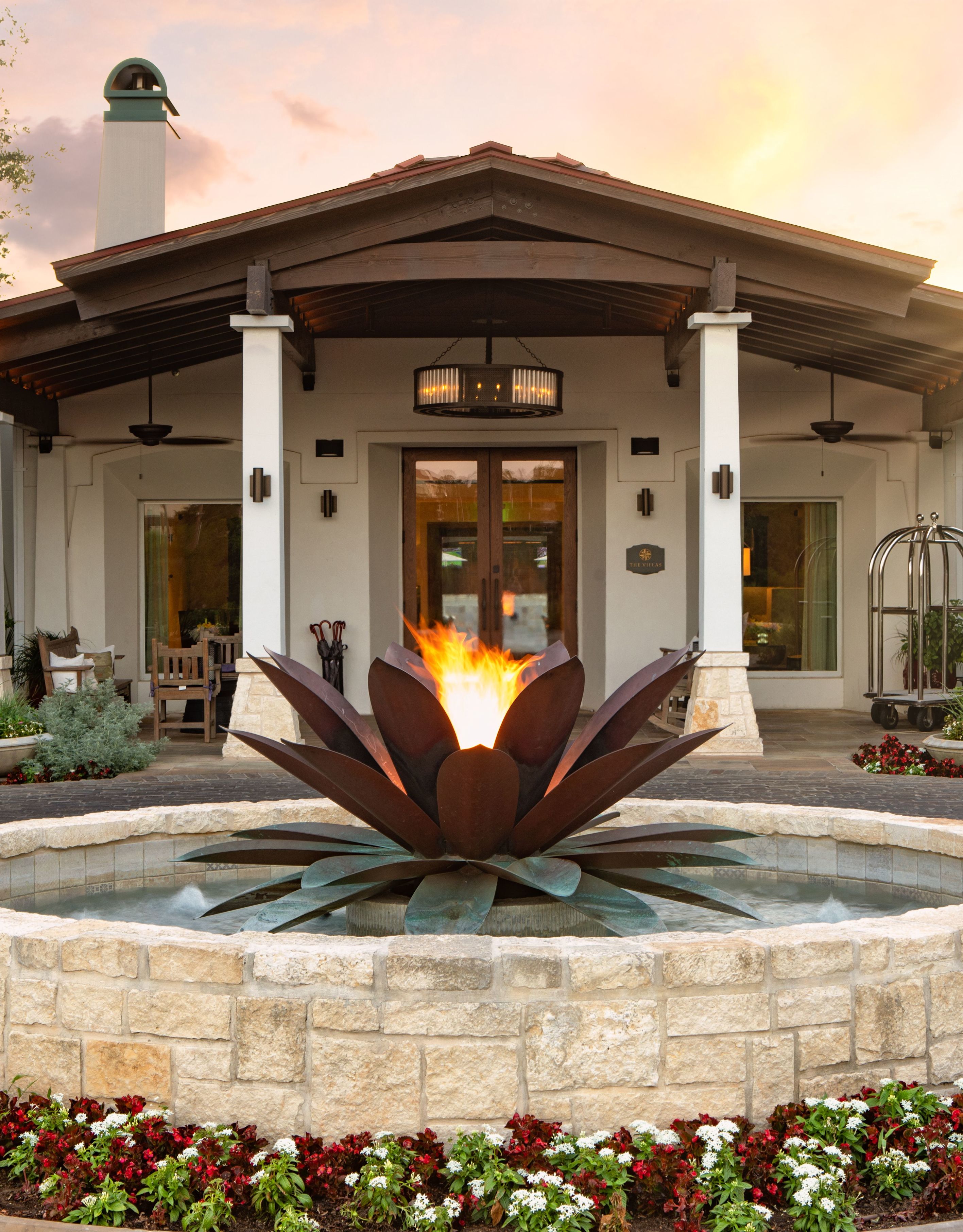 Water feature with large metal agave plant in the middle, in front of a villa on hotel grounds