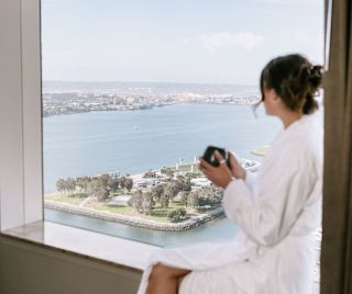 A Woman Enjoying the View of the Water from a Guest Room