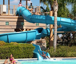 Personas paseando por el tobogán acuático y jugando en la piscina
