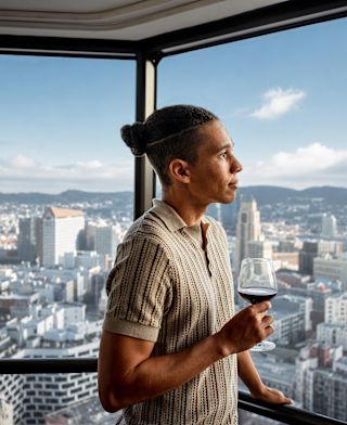 A man is looking out the window in a guest room with city view