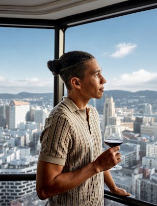 A man is looking out the window in a guest room with city view
