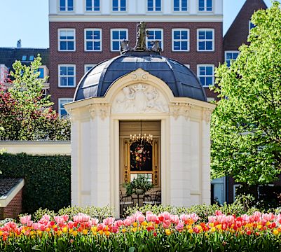 Paviljoen in een tuin met tulpen en bomen