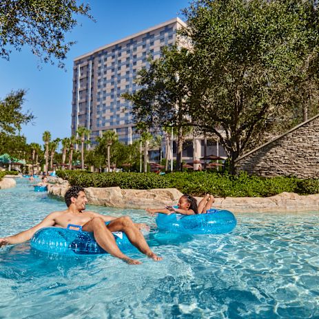 Homem e menina em tubos de borracha na área da piscina ao ar livre
