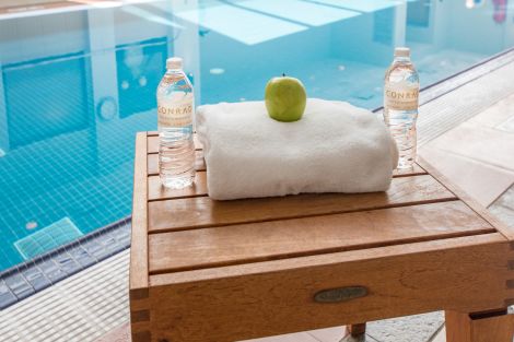 swimming pool, bottles of water, white towel, green apple