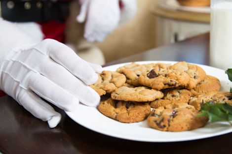 Hand Wearing a White Glove is Getting Chocolate Chip Cookies from a Plate