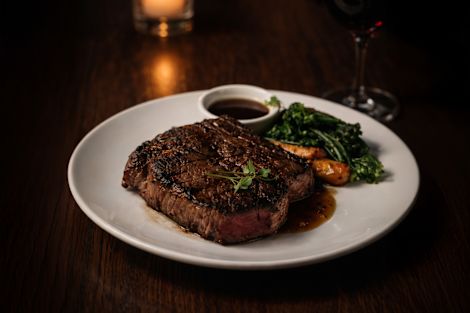 A Steak, Vegetables and Sauce on a Plate at Trader Vics Restaurant