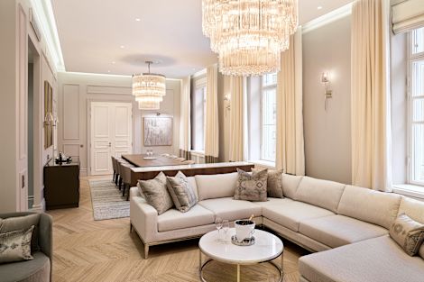 コーナーソファ、シャンデリア、8名様用のダイニングテーブルを備えたスイートのリビングルームとダイニングルーム