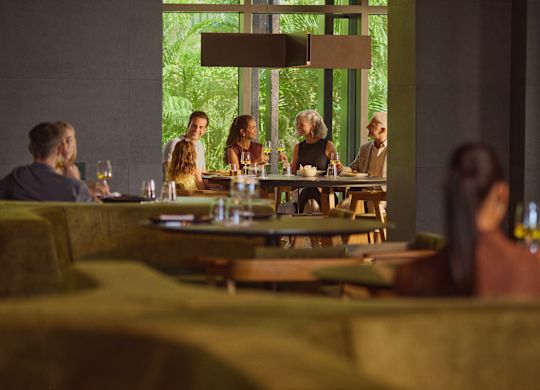 Familie formată din bunic, bunică, tată, mamă și fiică savurând o masă în restaurantul hotelului