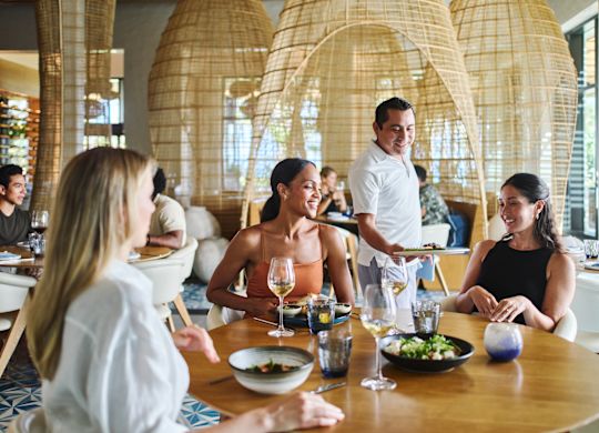 Groupe de personnes prenant un repas dans l’espace restaurant. Un membre du personnel sert de la nourriture