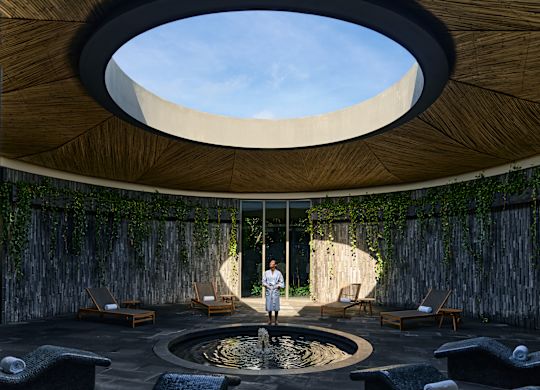 Espace spa avec un feu de lumière éclairant une partie circulaire du mur. Une personne se tient à la lumière