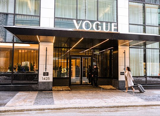 Femme marchant vers l’entrée de l’hôtel avec panneau de l’hôtel au-dessus de la tête