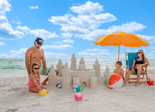 Familie jucându-se și făcând un castel de nisip pe plajă