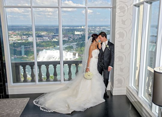 Newlyweds Holding in a Hotel Room with View of Niagara Falls