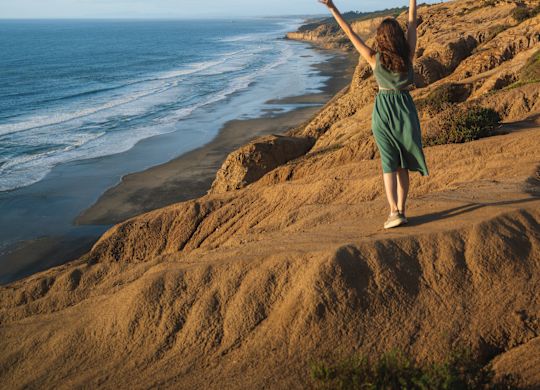 Kobieta stojąca obok plaży i ciesząca się oglądaniem ludzi na niebie