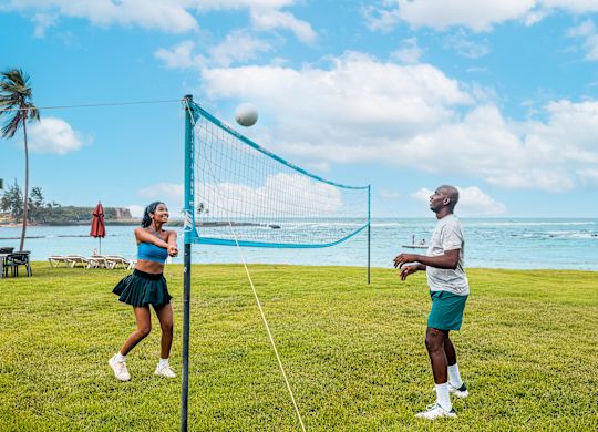 Couple Playing Volleyball on a Field next to the Water