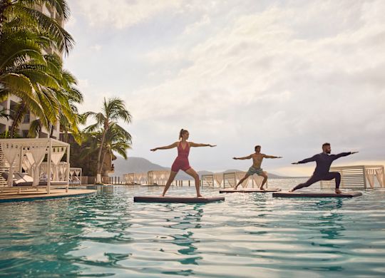 プールで水上ヨガを練習する女性と2人の男性