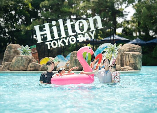 ครอบครัวกําลังมองกล้องพร้อมอุปกรณ์ลอยน้ําฟลามิงโก