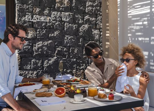 Familie entspannt im Schatten, Frau wischt Mädchen mit einem Taschentuch den Mund ab