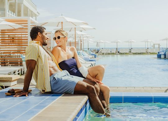 casal sentado ao lado da piscina ao ar livre