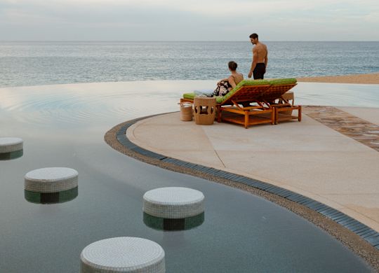 Cuplu relaxându-se în zona piscinei, cu vedere spre ocean