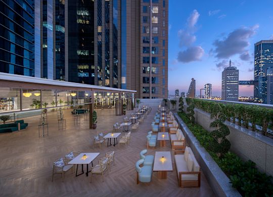 Der Meetingbereich "Avery" auf einer Terrasse mit Stadtblick am Abend