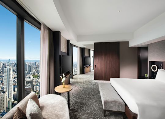 Large bed and seating area in a suite with city view