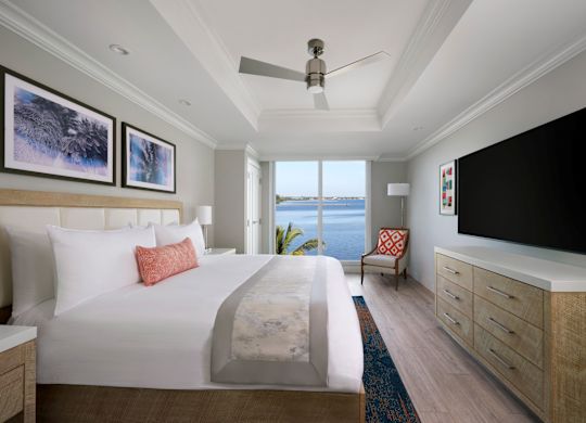 Tempat tidur dalam kamar dengan TV, seni di dinding, dan kursi