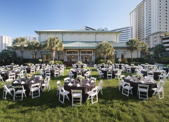 Kulaté stoly umístěné venku na trávníku na svatební hostinu