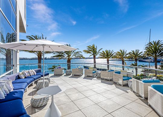 Odysea restaurant terrace, lounge chairs, umbrella, palm trees, view of the ocean