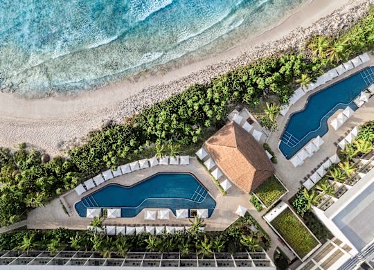 vue aérienne de l'extérieur de l'hôtel, deux piscines extérieures, des parasols et de la plage