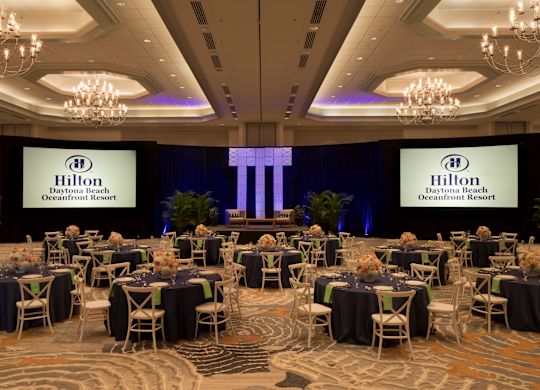 Yuvarlak Masalar, Sandalyeler ve İki Projeksiyon Ekranı bulunan Geniş Balo Salonu