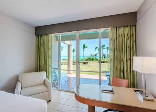 a work desk and a soft chair next to a patio door and ocean view
