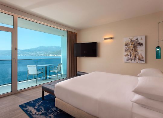 Chambre avec très grand lit et vue sur la mer depuis le balcon