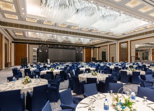 Balsalsarrangemang med vita täckta runda bord och blå täckta stolar