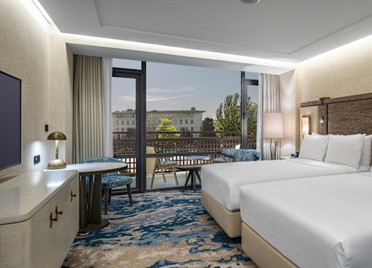 Two beds in room with TV, desk and chair
