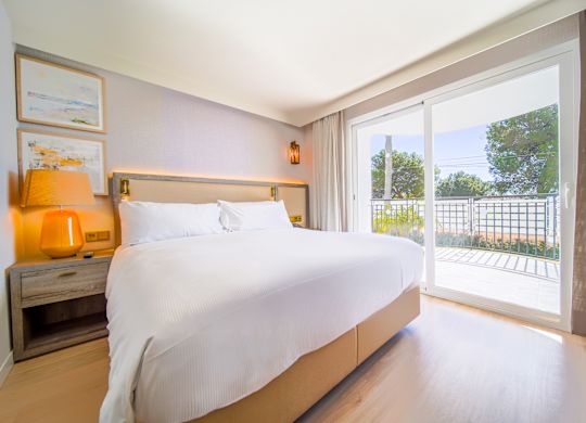 Camere și apartamente Un pat într-un apartament de hotel cu balcon