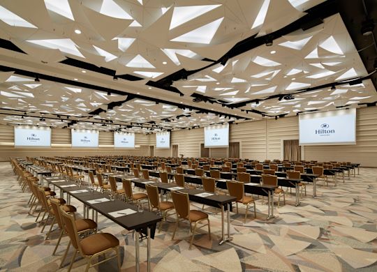 การจัดห้องเรียนในห้องประชุมพร้อมโต๊ะ เก้าอี้ หน้าจอการนําเสนอหกหน้าจอ และโพเดียม