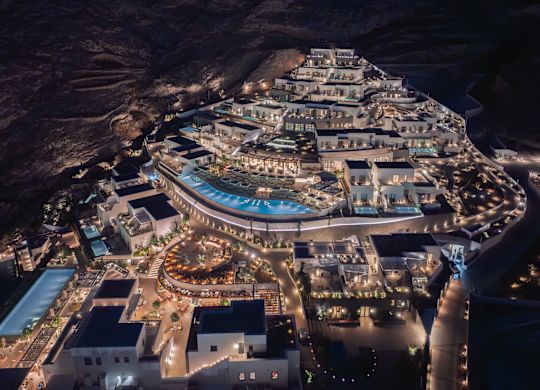 Luftaufnahme eines Resorts bei Nacht mit Swimmingpool und privaten Terrassen mit sanfter Beleuchtung.