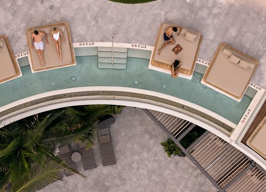 Oameni relaxându-se pe paturi de zi în zona piscinei