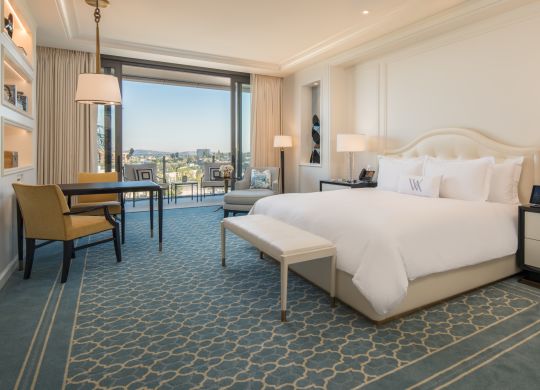 Deluxe King Room with king bed, footrest, lounge chair, work desk, and balcony with outdoor view