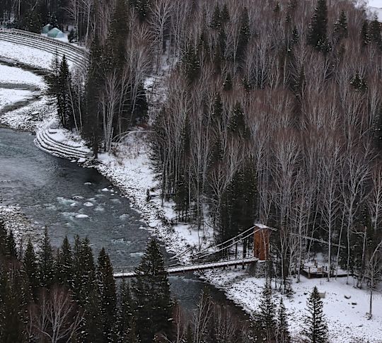 Peisaj zăpezit cu pod din lemn traversând râul
