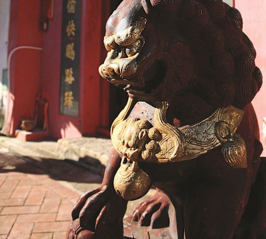 紅色寺廟入口前的石獅雕像,有中國標誌。