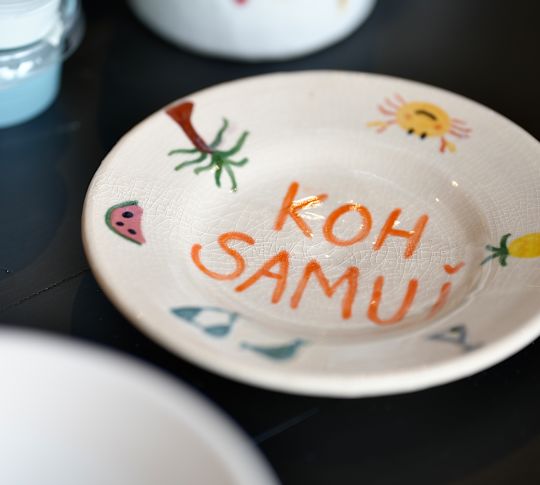 Eine dekorierte Töpferplatte mit Koh Samui, die mit orangefarbenen Buchstaben versehen ist