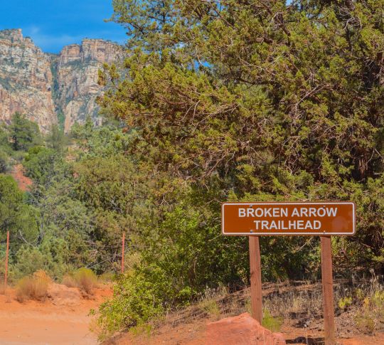 Sign for Broken Arrow trail with trees and landscape in background