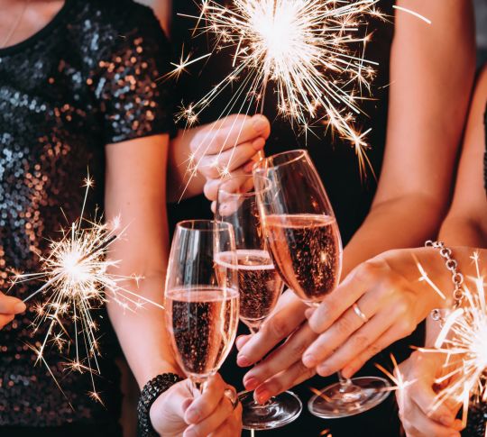 Closeup of women's hands holding glasses of champagne and sparklers