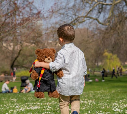Young boy with teddy bear in park