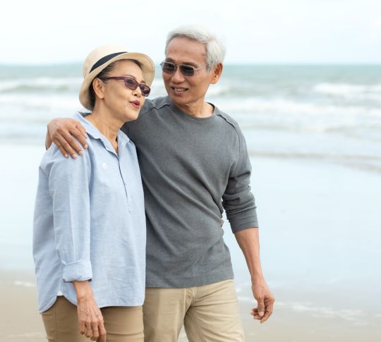 Older couple walking on beach together