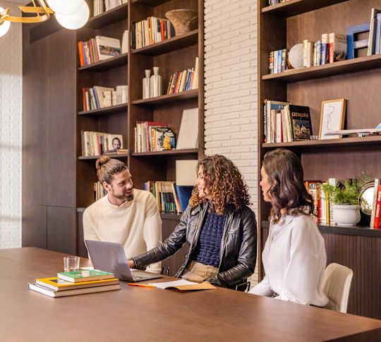 Group of people in meeting space with laptop and books