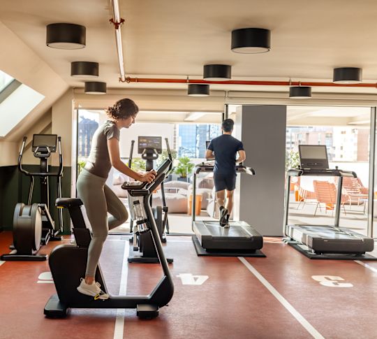 Fitness center with man and woman on cardio machines