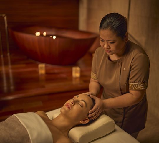 Woman on treatment table receiving head massage